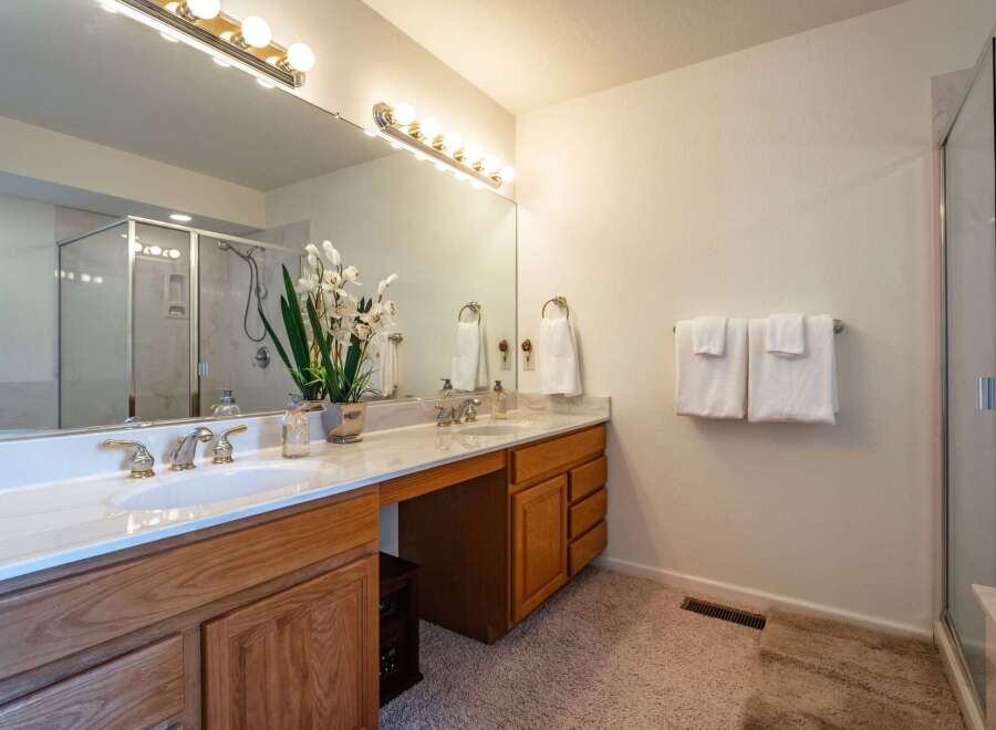 This spacious bathroom features a double vanity with elegant gold fixtures and a large mirror, perfect for busy mornings.