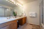 This spacious bathroom features a double vanity with elegant gold fixtures and a large mirror, perfect for busy mornings.