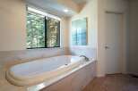 Indulge in relaxation in this luxurious bathroom featuring a spacious soaking tub with a stunning view of the surrounding forest.