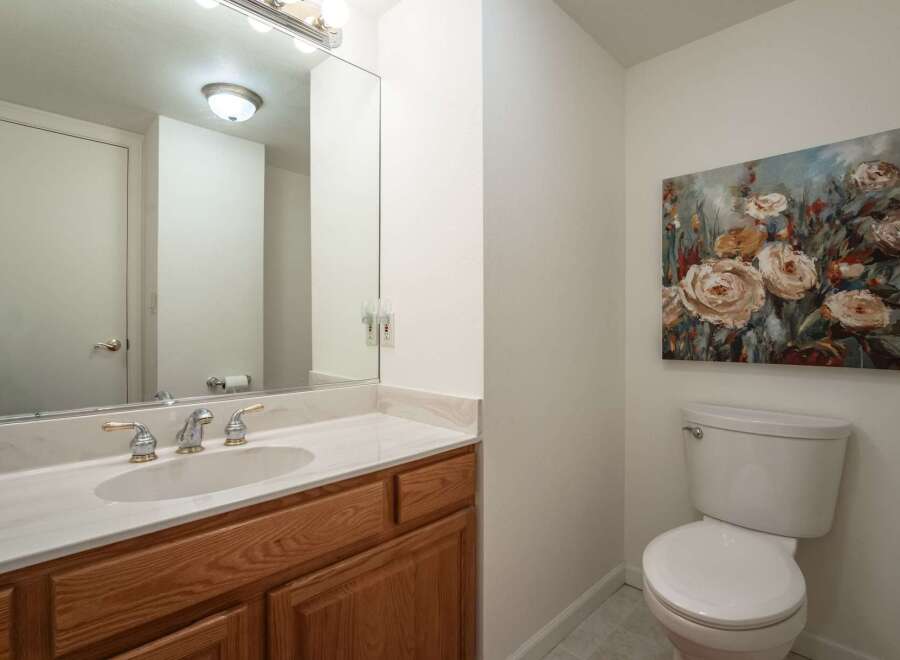 This charming bathroom features a spacious vanity with a marble countertop and a wooden cabinet, perfect for storage.