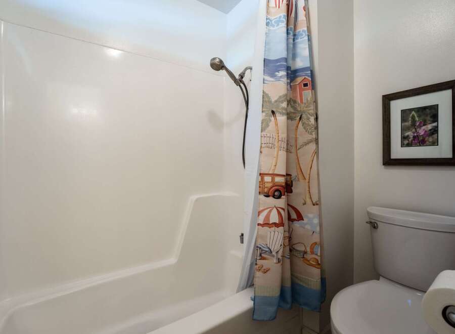 This bathroom features a clean white bathtub and shower combo, perfect for relaxing after a long day.