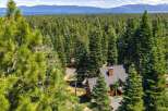 Nestled amidst a dense forest of towering pine trees, this charming home offers a serene retreat with breathtaking views of a distant lake and mountains.