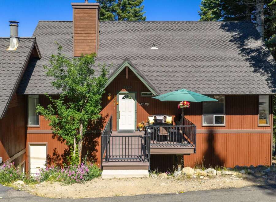 Charming mountain home featuring a warm, rustic exterior with rich wood siding and a prominent stone chimney.
