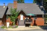 Charming mountain home featuring a warm, rustic exterior with rich wood siding and a prominent stone chimney.