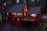 Nestled amidst towering trees, this charming red cabin offers a cozy retreat with its warm interior lights glowing invitingly.