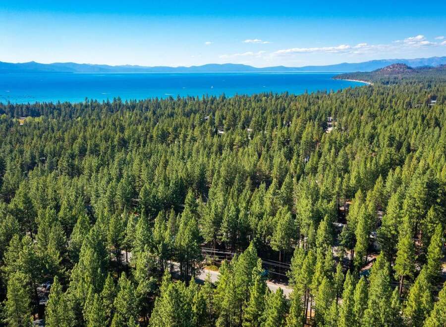 Experience the ultimate mountain lifestyle with this stunning aerial view of a property nestled within a dense pine forest.