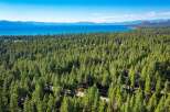 Experience the ultimate mountain lifestyle with this stunning aerial view of a property nestled within a dense pine forest.