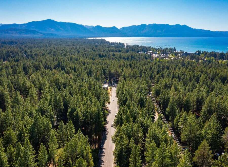 Experience the ultimate mountain lifestyle with this stunning aerial view of a property nestled amidst a dense pine forest.