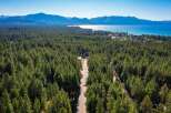 Experience the ultimate mountain lifestyle with this stunning aerial view of a property nestled amidst a dense pine forest.