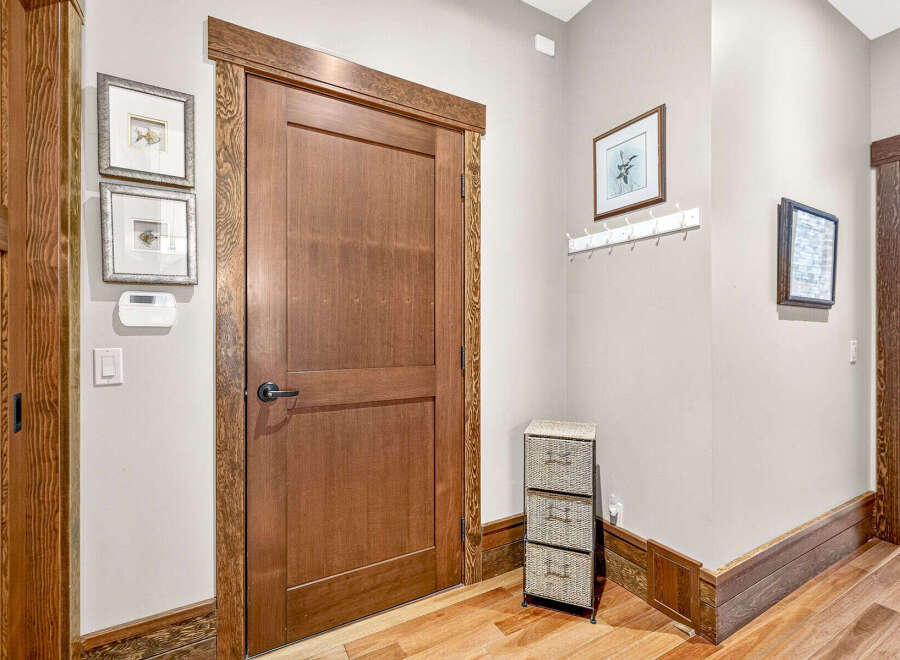 This inviting entryway features a beautiful solid wood door with a modern black handle, complemented by intricate wood trim.