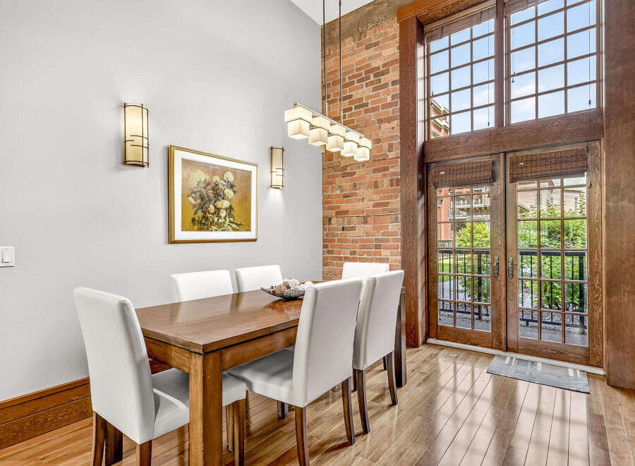 Experience industrial-chic living in this stunning dining area, featuring exposed brick walls and a soaring ceiling.