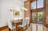 Experience industrial-chic living in this stunning dining area, featuring exposed brick walls and a soaring ceiling.
