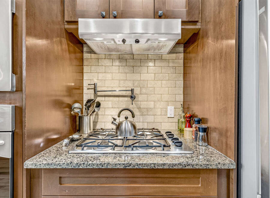 This kitchen features a sleek stainless steel gas range with a modern pot filler above.