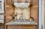 This kitchen features a sleek stainless steel gas range with a modern pot filler above.