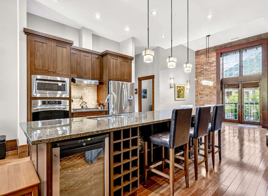 Experience luxury living in this stunning kitchen featuring rich wood cabinetry, granite countertops, and a spacious island with bar seating.