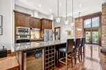 Experience luxury living in this stunning kitchen featuring rich wood cabinetry, granite countertops, and a spacious island with bar seating.