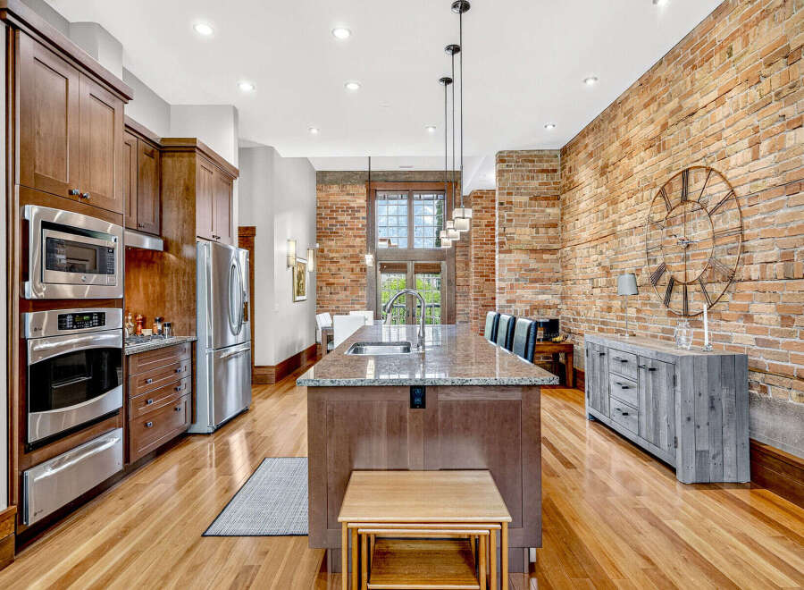 Experience industrial-chic living in this stunning kitchen featuring exposed brick walls and warm wood cabinetry.