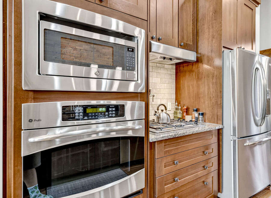 This kitchen boasts a sleek, modern design with stainless steel appliances, including a built-in microwave and oven.