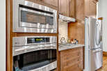 This kitchen boasts a sleek, modern design with stainless steel appliances, including a built-in microwave and oven.