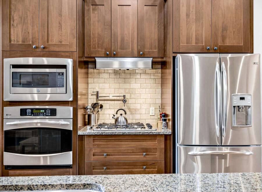 Experience modern convenience in this kitchen featuring stainless steel appliances, including a built-in microwave, oven, and a spacious side-by-side refrigerator with an ice dispenser.