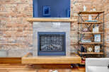 Experience rustic charm with this exposed brick fireplace, featuring a modern gas insert and a thick wooden mantel.
