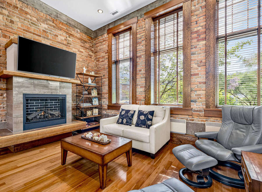 Experience industrial-chic living in this stunning loft featuring exposed brick walls and a modern fireplace.