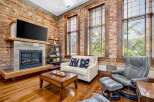 Experience industrial-chic living in this stunning loft featuring exposed brick walls and a modern fireplace.