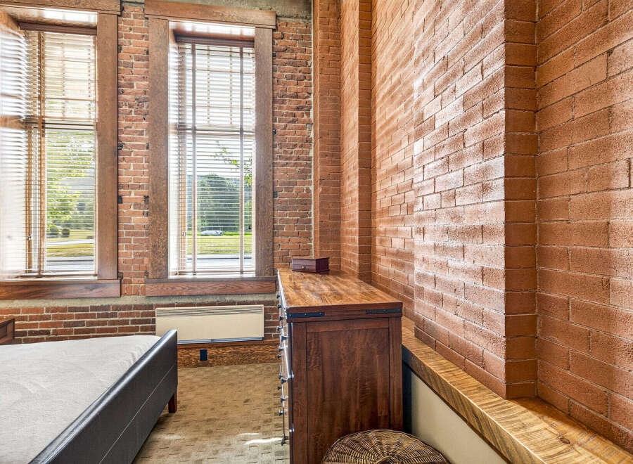 Exposed brick walls and large windows create an industrial-chic aesthetic in this bedroom.