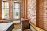Exposed brick walls and large windows create an industrial-chic aesthetic in this bedroom.