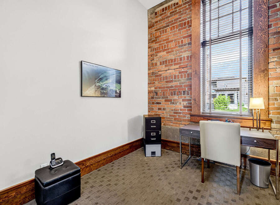 This office space features a large window with blinds, offering ample natural light and a view of the outdoors.