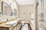 This luxurious bathroom features a spacious double vanity with granite countertops and vessel sinks, complemented by modern chrome fixtures.