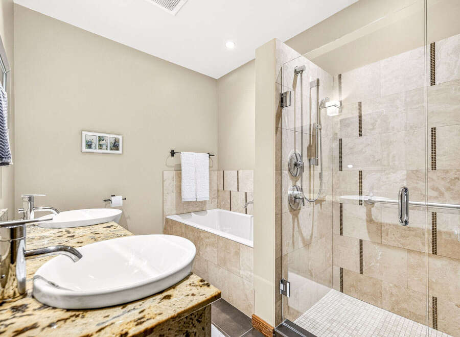 This luxurious bathroom features a spacious walk-in shower with elegant tilework and a glass enclosure, complemented by a deep soaking tub.