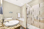 This luxurious bathroom features a spacious walk-in shower with elegant tilework and a glass enclosure, complemented by a deep soaking tub.