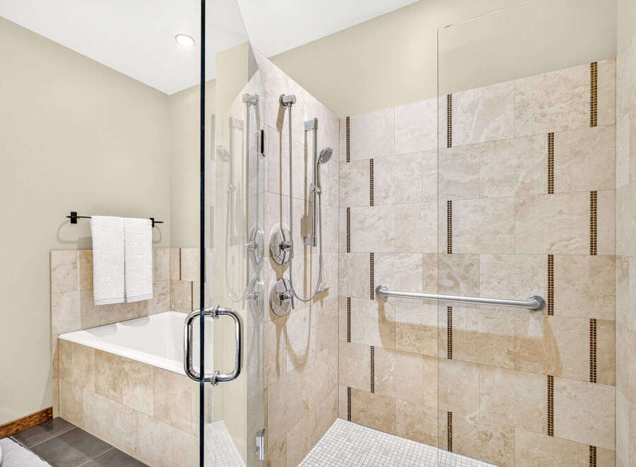 Experience luxury and accessibility in this stunning bathroom, featuring a spacious walk-in shower with multiple shower heads and a convenient grab bar.
