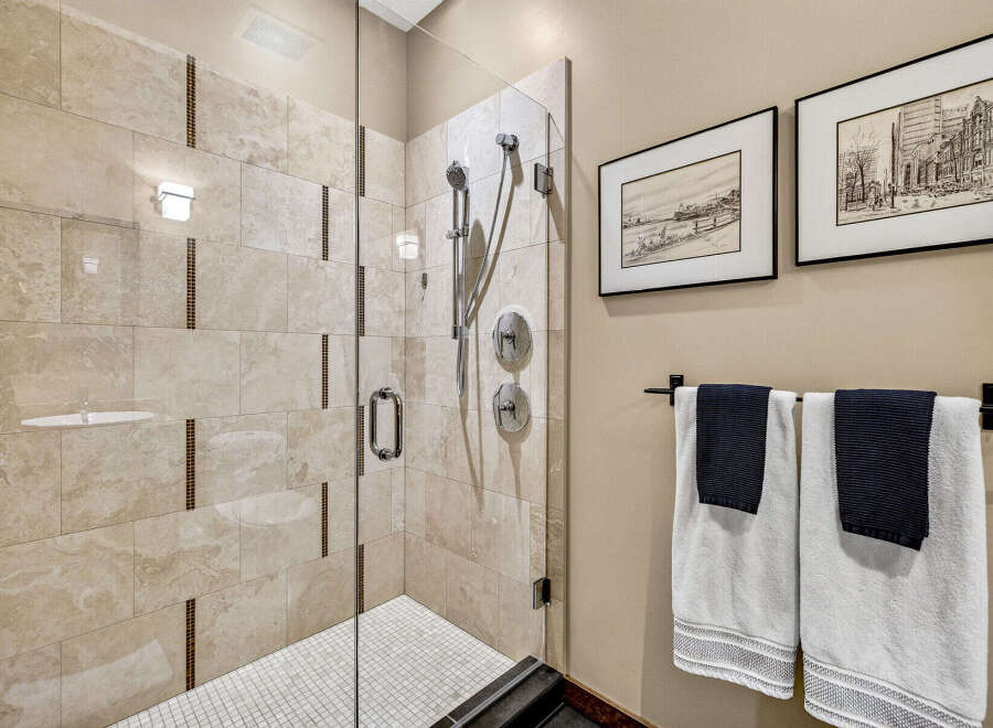 Experience luxury in this stunning bathroom featuring a spacious glass-enclosed shower with elegant marble-look tiles and decorative mosaic accents.