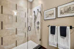 Experience luxury in this stunning bathroom featuring a spacious glass-enclosed shower with elegant marble-look tiles and decorative mosaic accents.