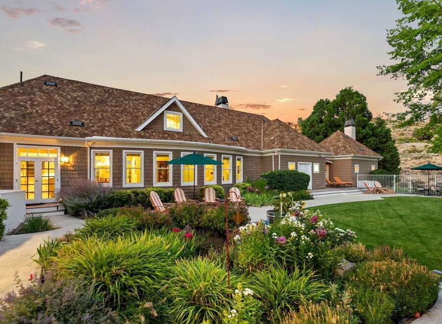 This stunning home boasts a beautifully landscaped backyard perfect for entertaining, featuring a lush green lawn, vibrant flower beds, and a serene patio area.