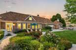 This stunning home boasts a beautifully landscaped backyard perfect for entertaining, featuring a lush green lawn, vibrant flower beds, and a serene patio area.