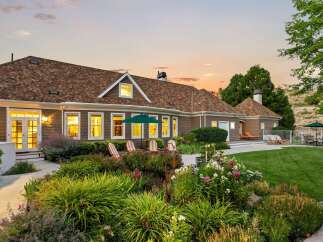 This stunning home boasts a beautifully landscaped backyard perfect for entertaining, featuring a lush green lawn, vibrant flower beds, and a serene patio area.