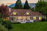 This charming home features a spacious deck overlooking a lush green lawn and scenic mountain views.