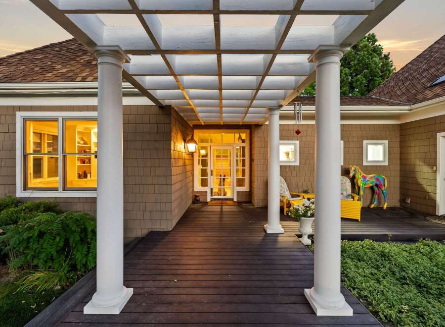 Step into this charming home through a welcoming covered porch featuring a white pergola and elegant columns.