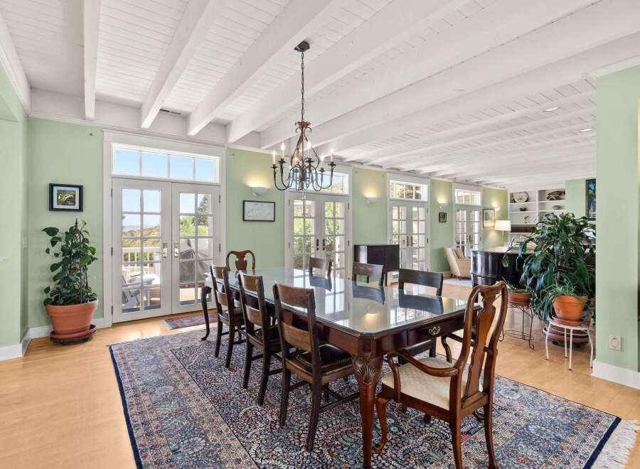 Experience elegant dining in this spacious room, featuring a large glass-top table surrounded by classic wooden chairs.