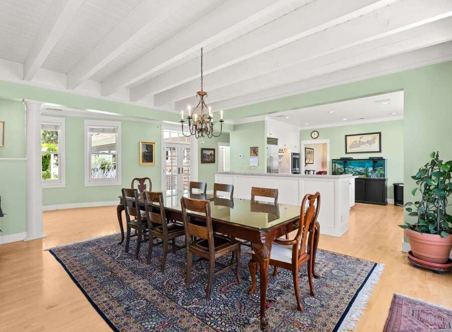 Experience elegant dining in this spacious room, featuring a large wooden table with seating for eight, set upon a beautiful oriental rug.
