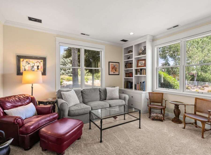This inviting living room features a plush burgundy leather armchair and ottoman, complemented by a comfortable gray sofa.