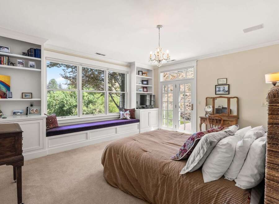 This charming bedroom features a large bay window with a built-in cushioned seat, perfect for enjoying the lush green views.