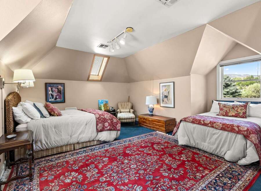 This charming attic bedroom features two comfortable beds adorned with elegant red and white patterned bedding, perfect for accommodating guests.
