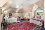 This charming attic bedroom features two comfortable beds adorned with elegant red and white patterned bedding, perfect for accommodating guests.