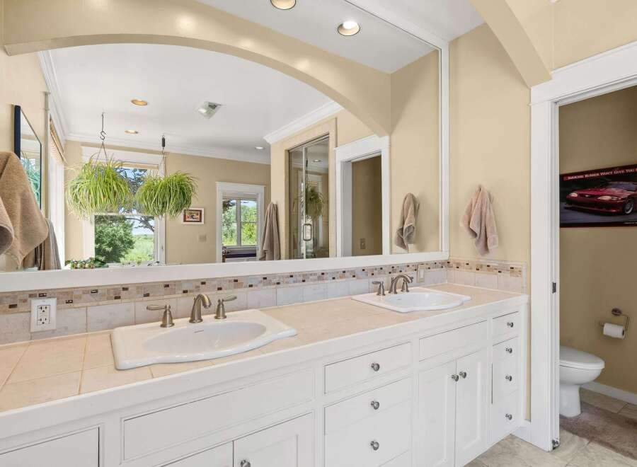 This spacious bathroom features a double vanity with two sinks, ample counter space, and elegant tile accents.