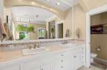 This spacious bathroom features a double vanity with two sinks, ample counter space, and elegant tile accents.
