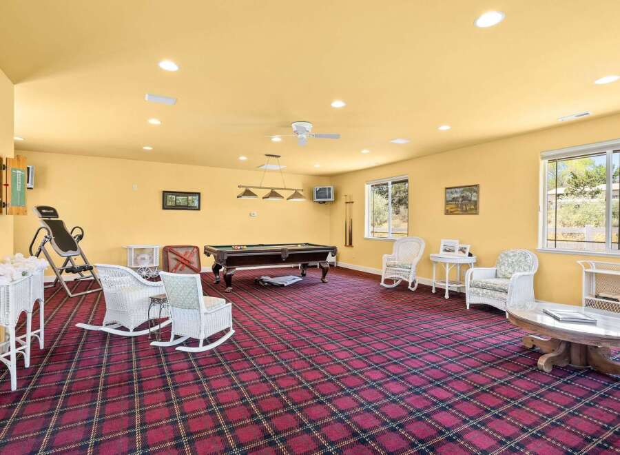 This spacious recreation room offers a perfect blend of entertainment and relaxation, featuring a full-size pool table for friendly games and comfortable wicker seating areas for guests to unwind.